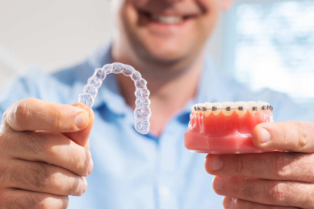Man holding up braces and Invisalign.
